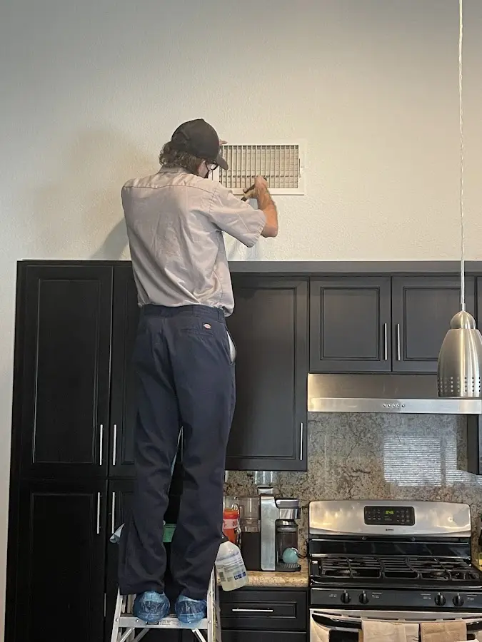 Technician inspecting an air vent during HVAC service in Plantation